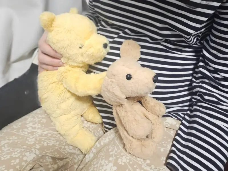 ヨメのお腹に耳を当てて胎動を感じ取ろうとするプーとイヌのぬいぐるみ
